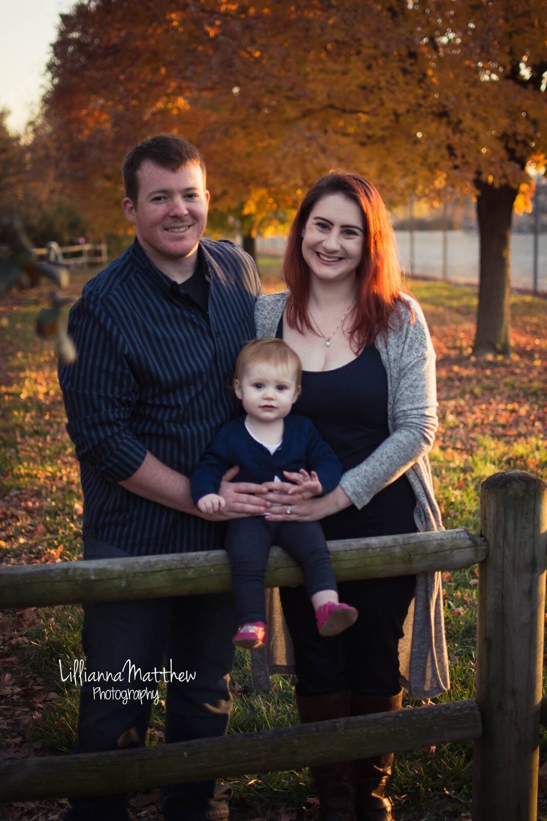 Family portrait by a wooden fence at golden hour, everyone smiling