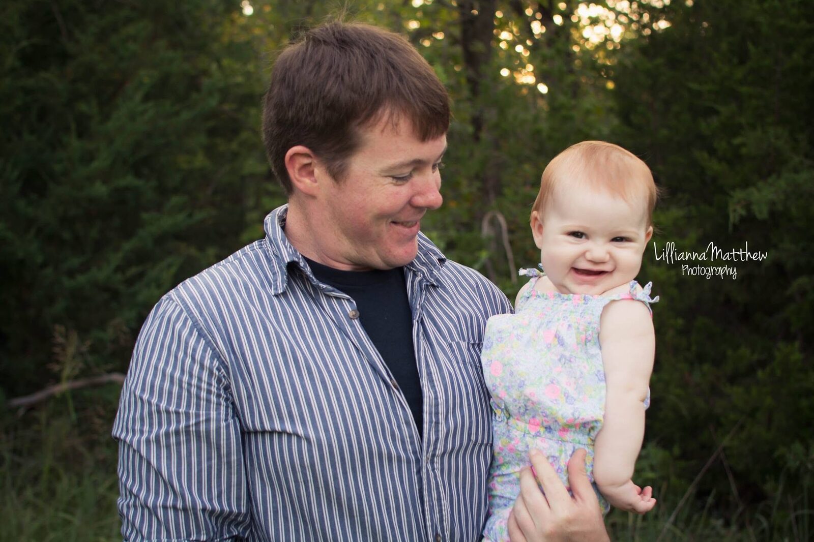 Dad holding his baby at golden hour, both smiling