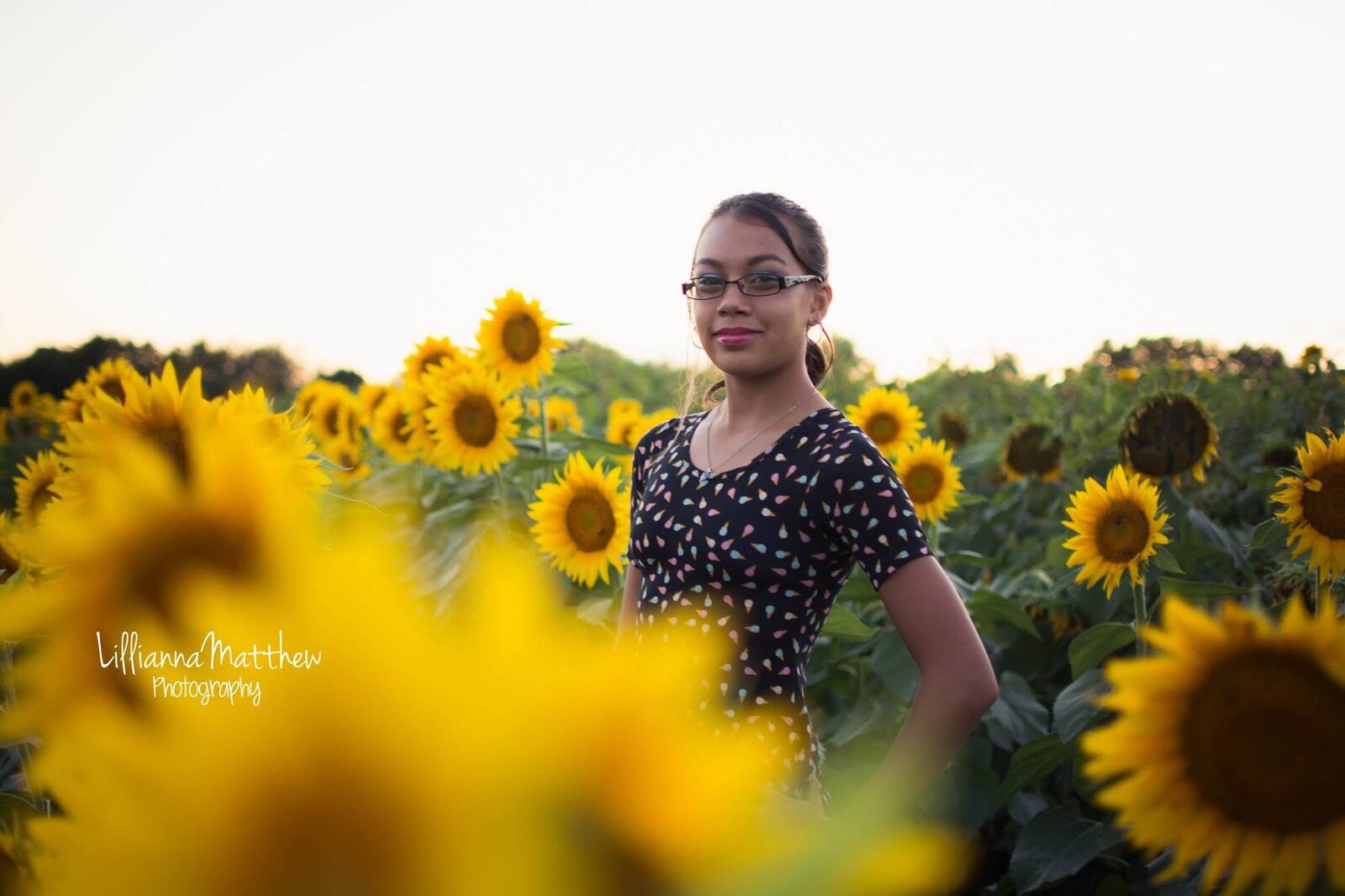 Daughter portrait with blurred sunflowers in the foreground