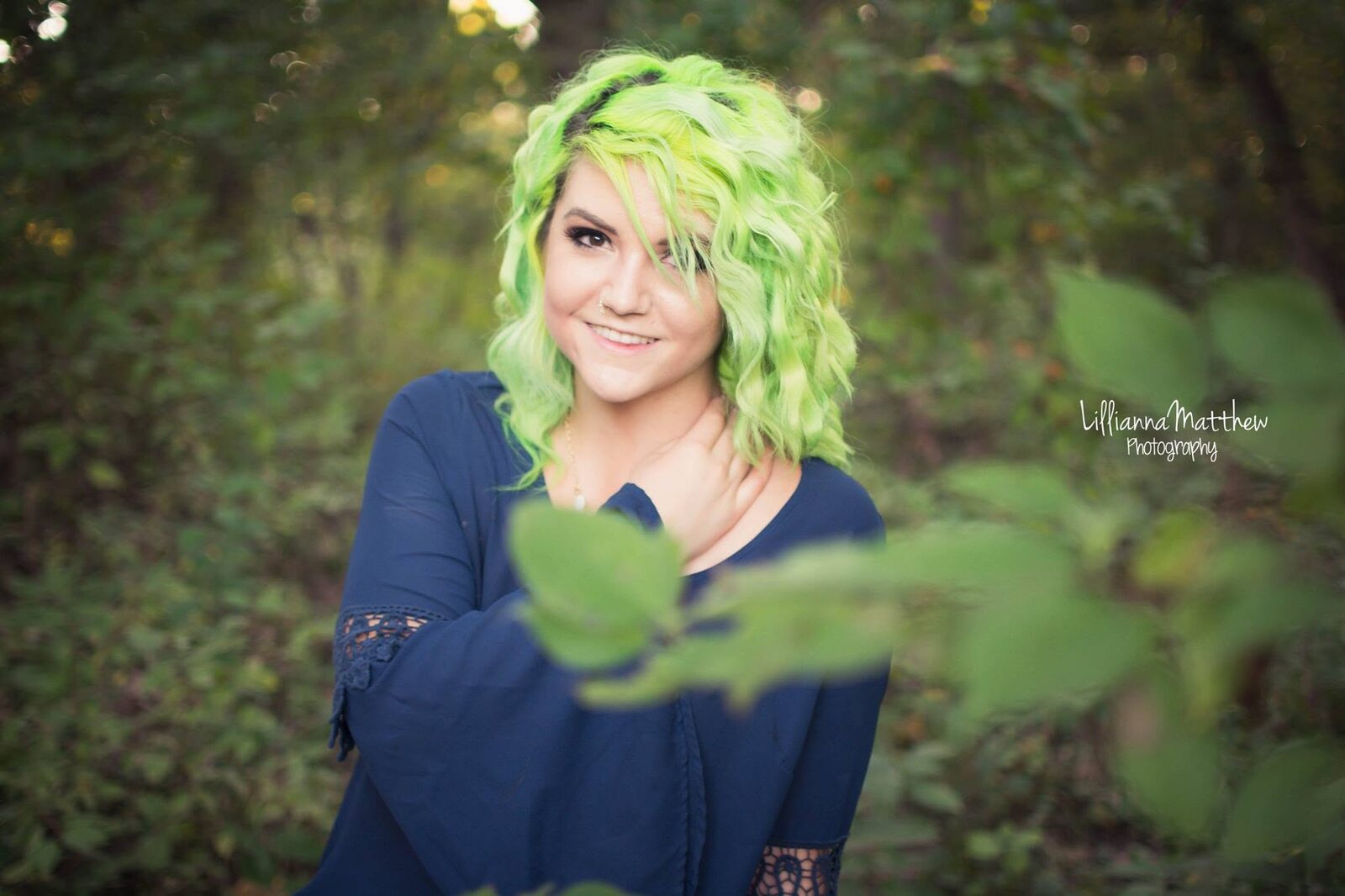 Close-up portrait with green-toned hair and a leaf in the foreground