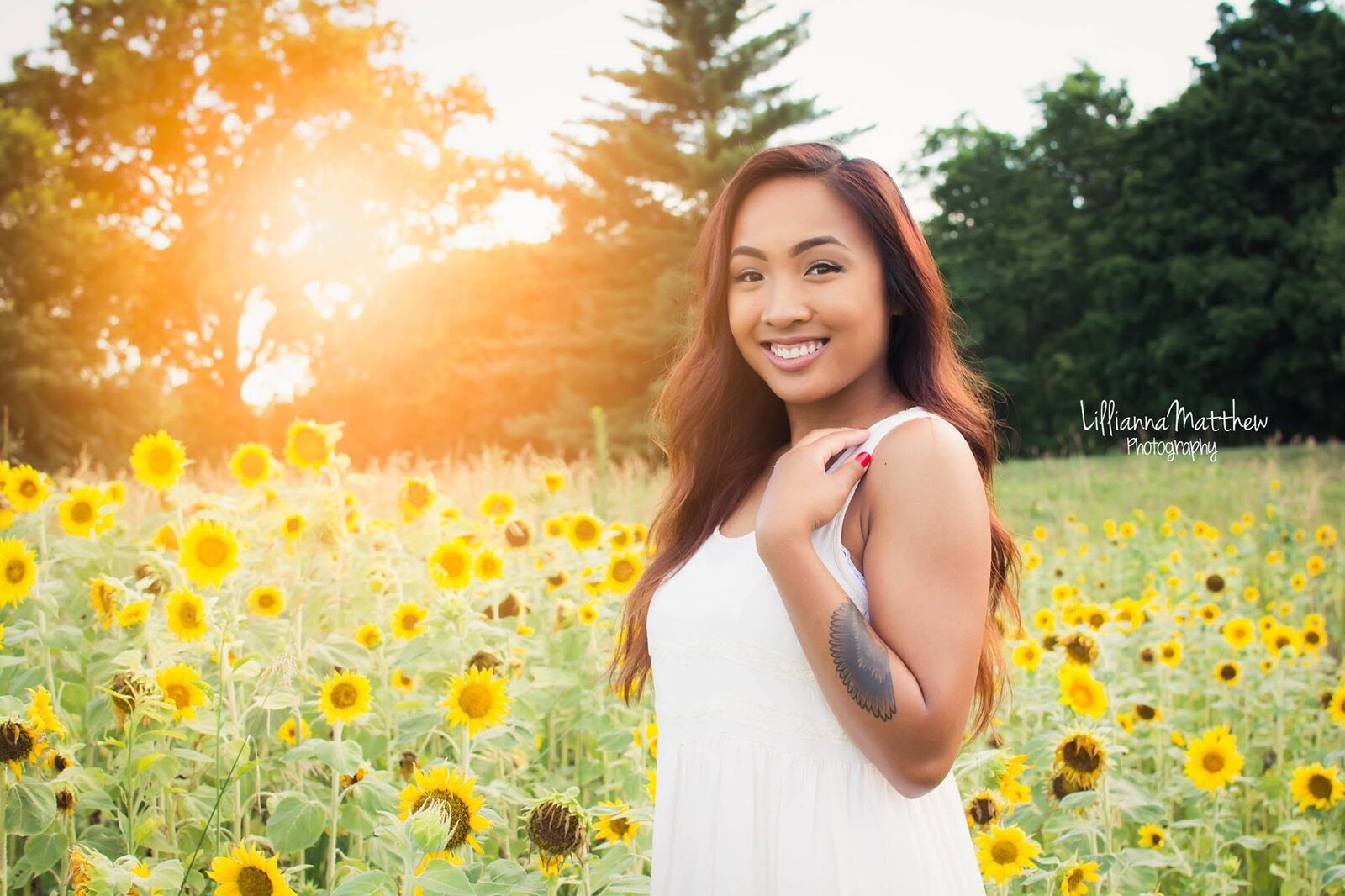 Golden-hour portrait with a sun flare in a sunflower field