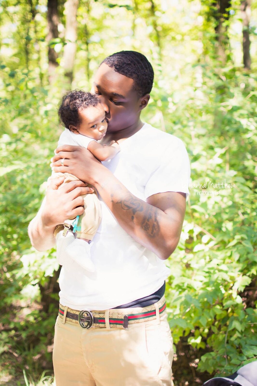Father holding his baby in the woods, both faces lit by warm light