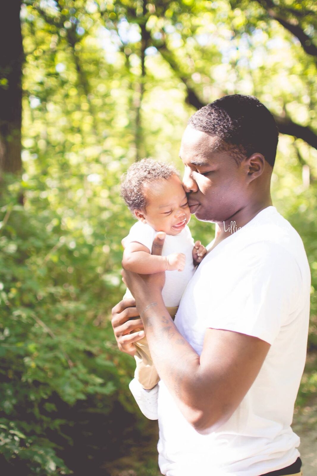 Father kissing his baby's forehead while the baby laughs joyfully