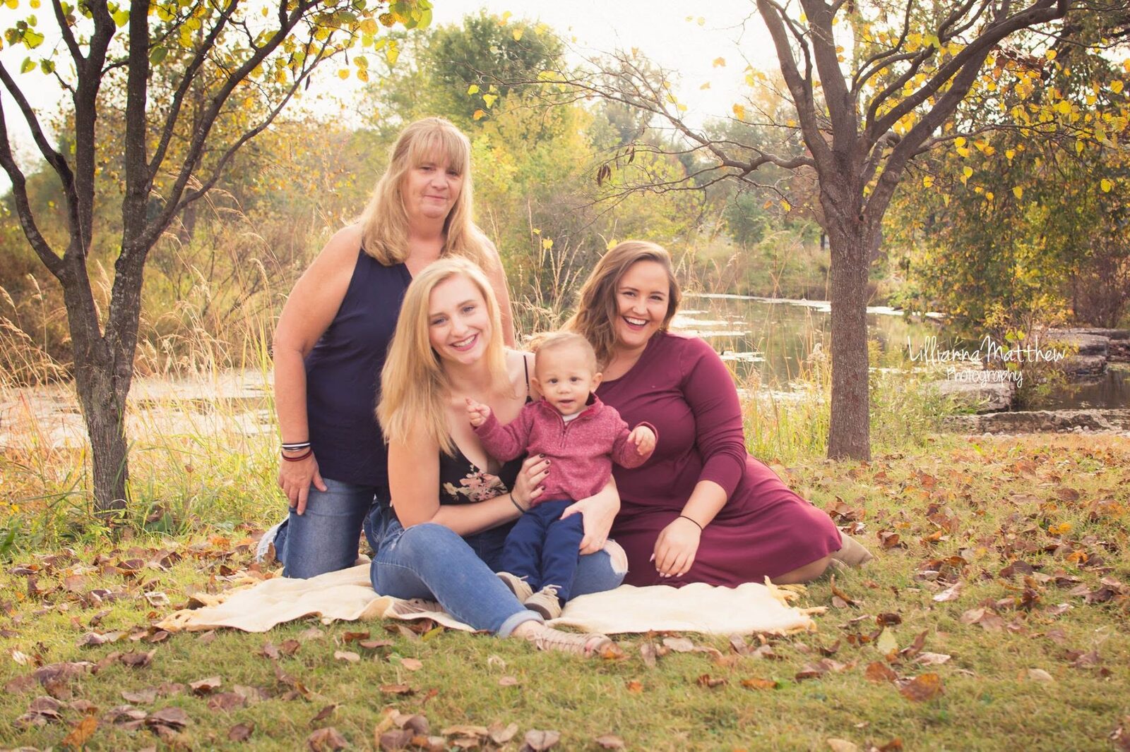Grandmother, mother, and aunt with a baby boy, backlit by golden autumn trees