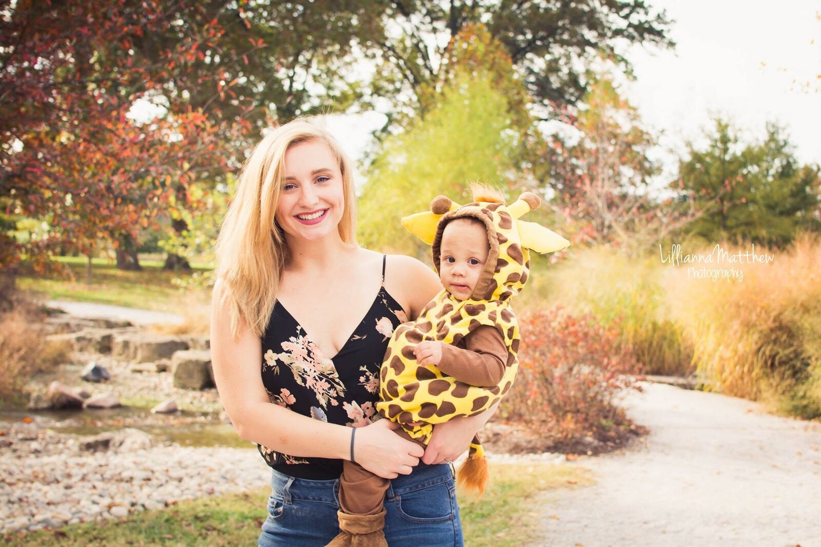 Blonde mother holding her baby, dressed in a yellow and brown giraffe costume