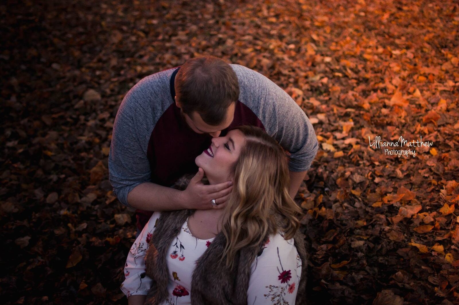 Man cupping his partner's face for a tender moment amid fallen autumn leaves