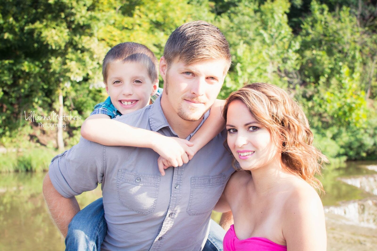 Full family portrait outdoors, all three smiling at the camera