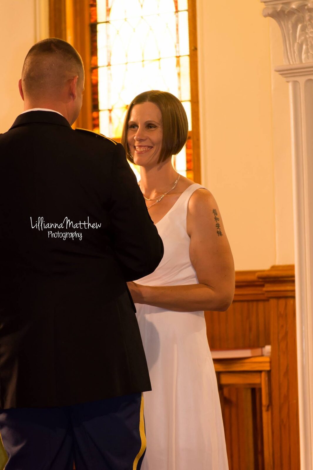 Bride smiling at her husband from behind, framed by a stained glass window