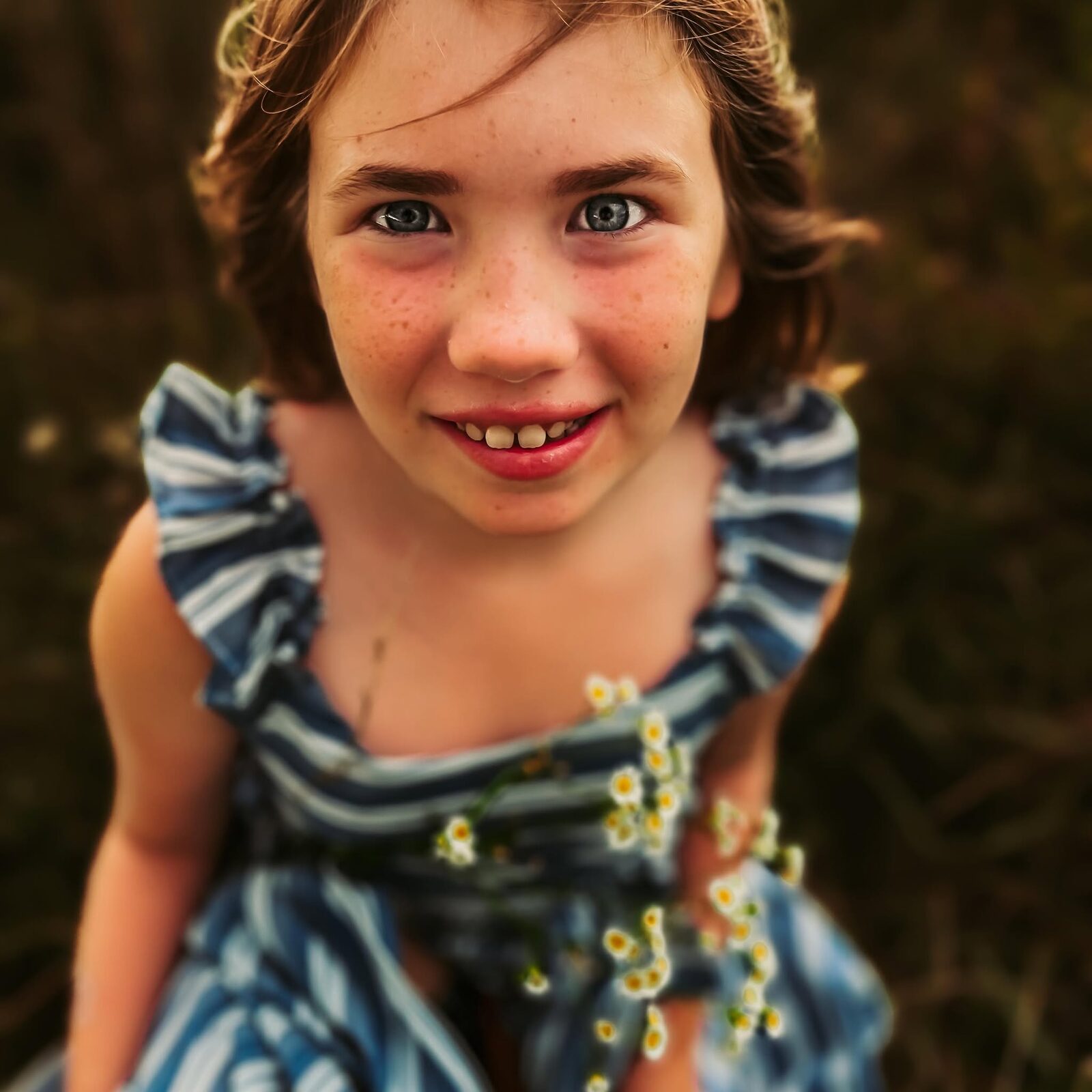 Close-up portrait of a girl smiling in a blue and white daisy-print dress