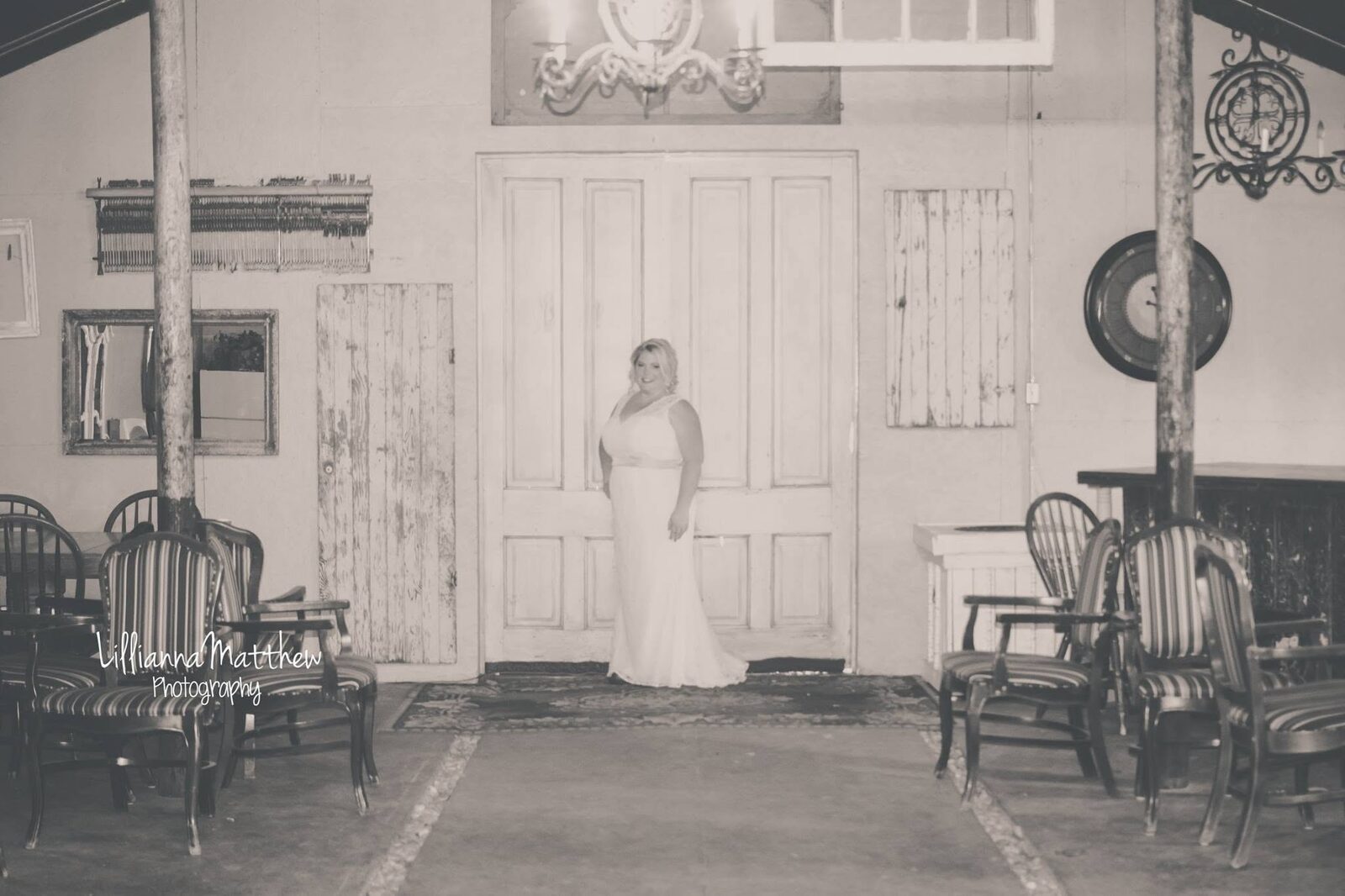 Black and white portrait of a bride standing in a vintage doorway at the reception venue