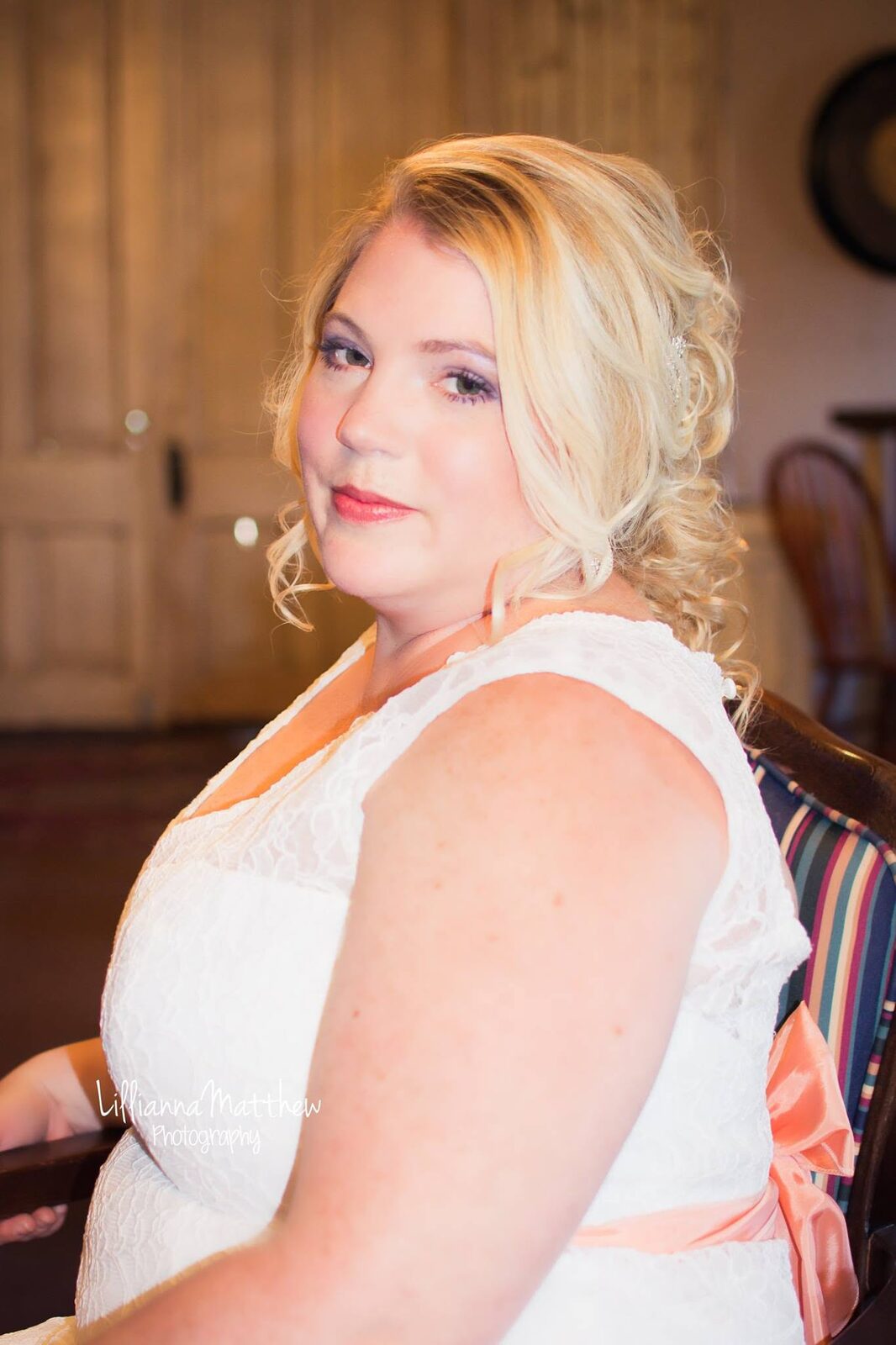 Bride in profile with soft curls and a peach sash, looking over her shoulder