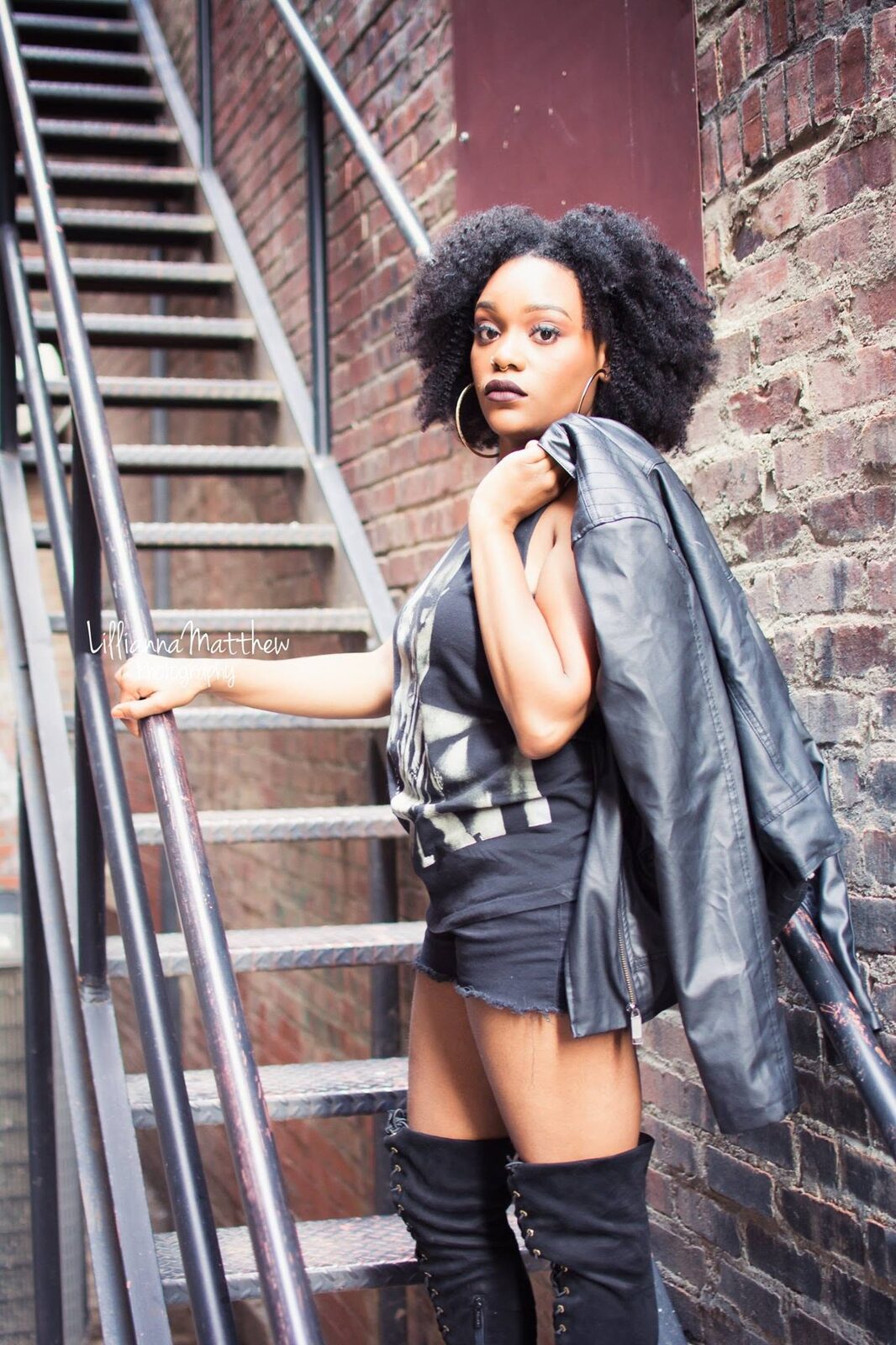 Edgy fashion portrait in a leather jacket and boots on a fire escape