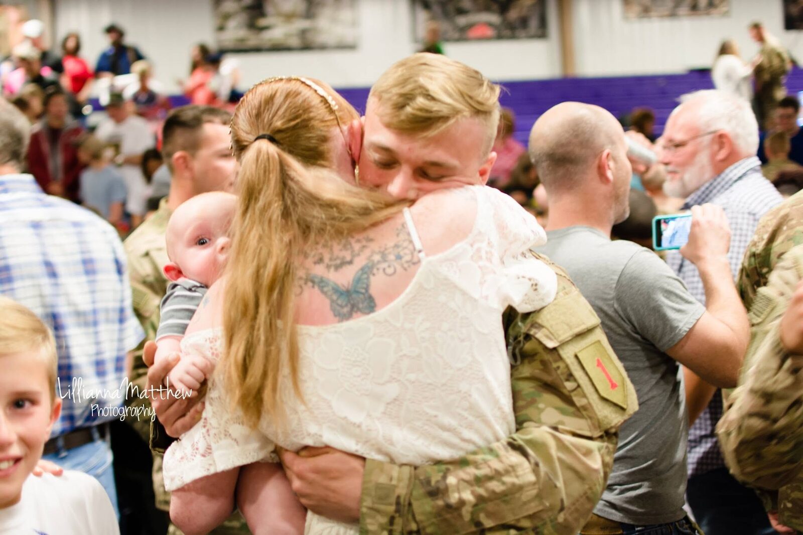 Full family reunion embrace, including a baby held by mom