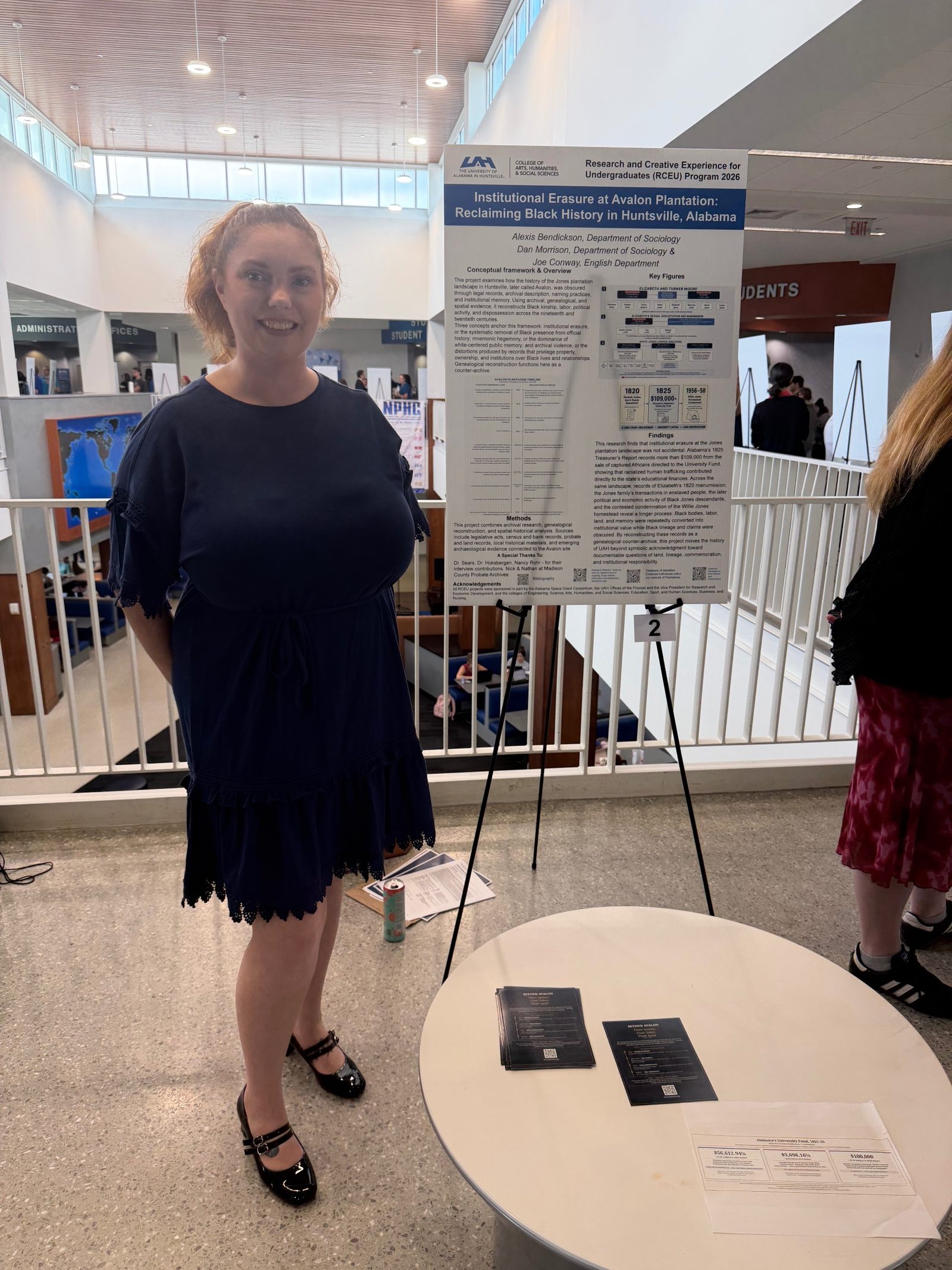 Alexis Bendickson standing beside her Beyond Avalon research poster at the UAH Summer Community of Scholars poster session