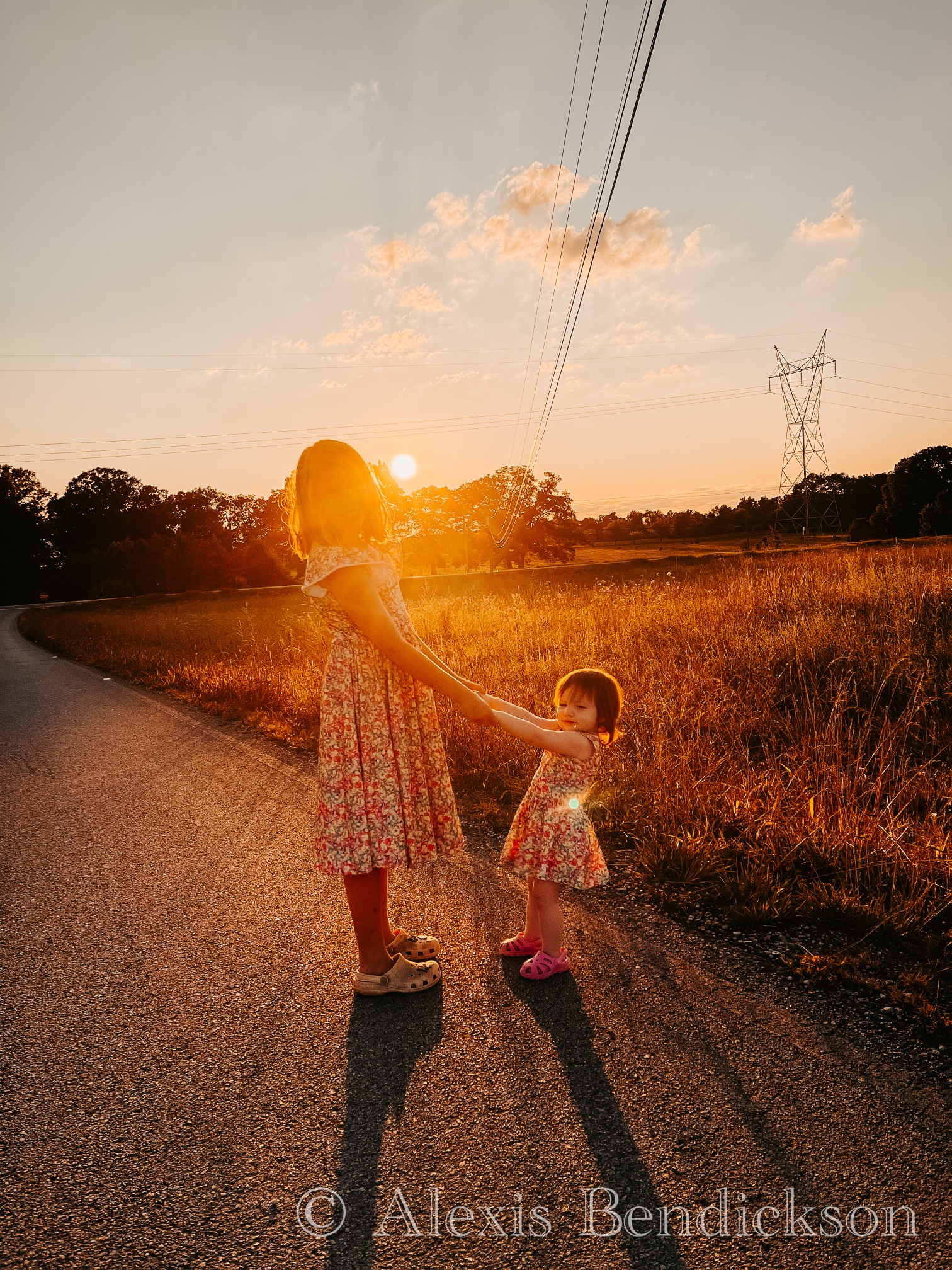 Arianna and Emme holding hands in a field at sunset