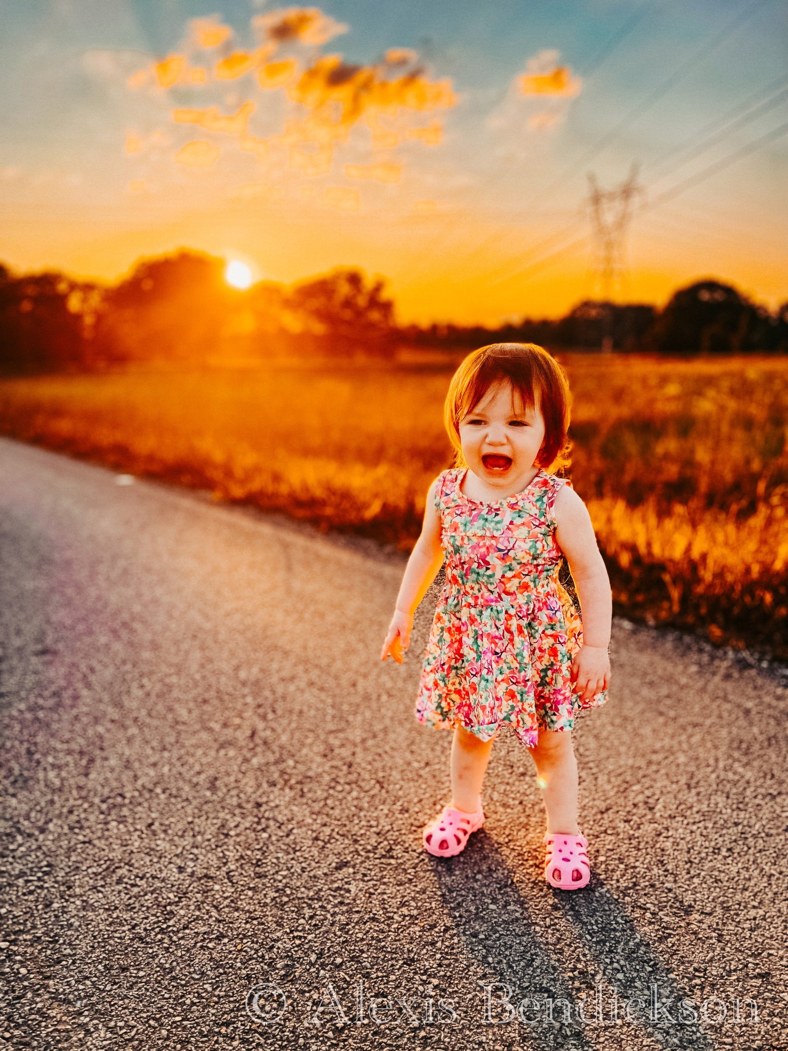 Arianna and Emme sitting together on a road at sunset, both smiling