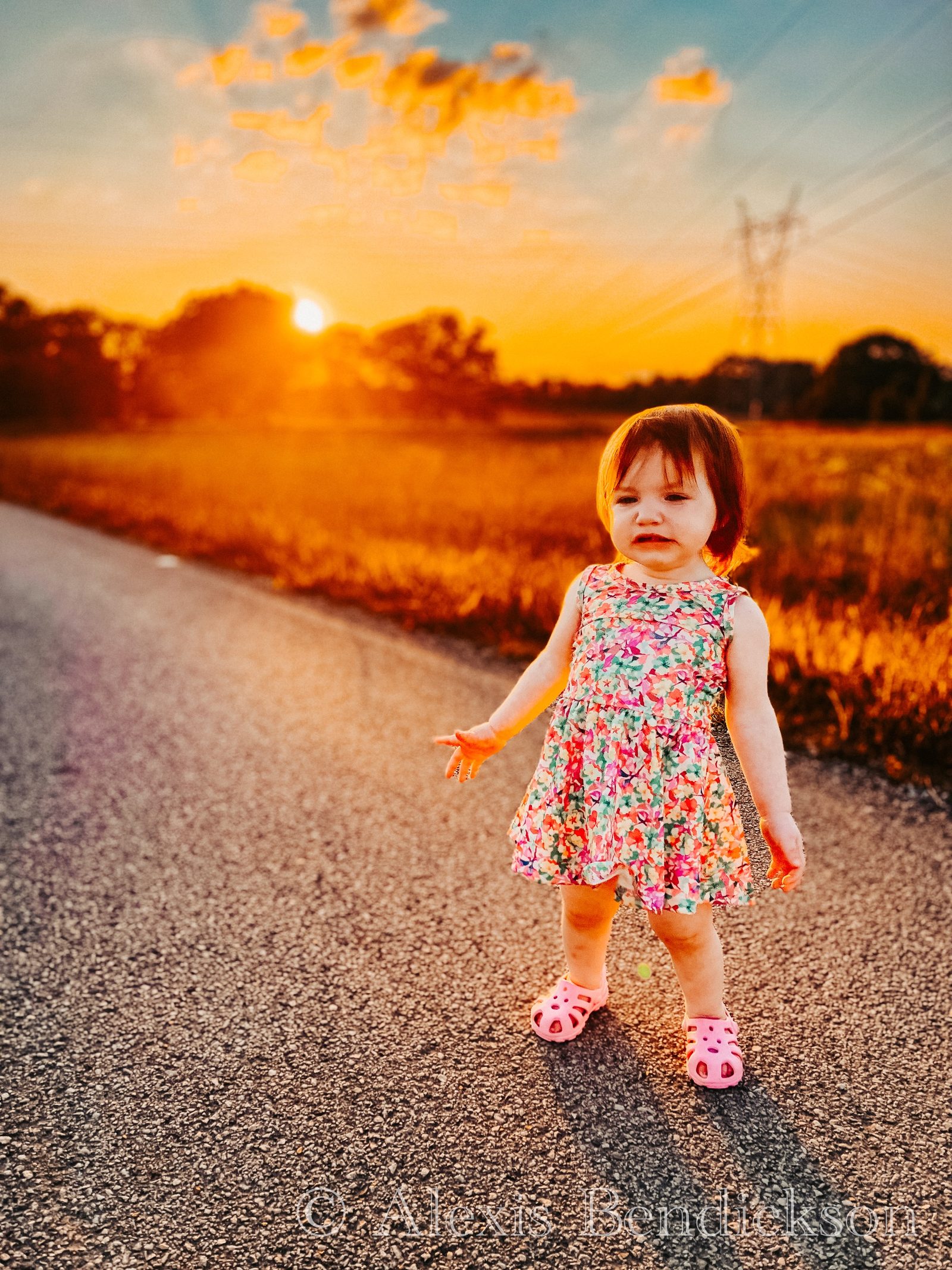 Emme toddling down a country road at sunset in pink sandals
