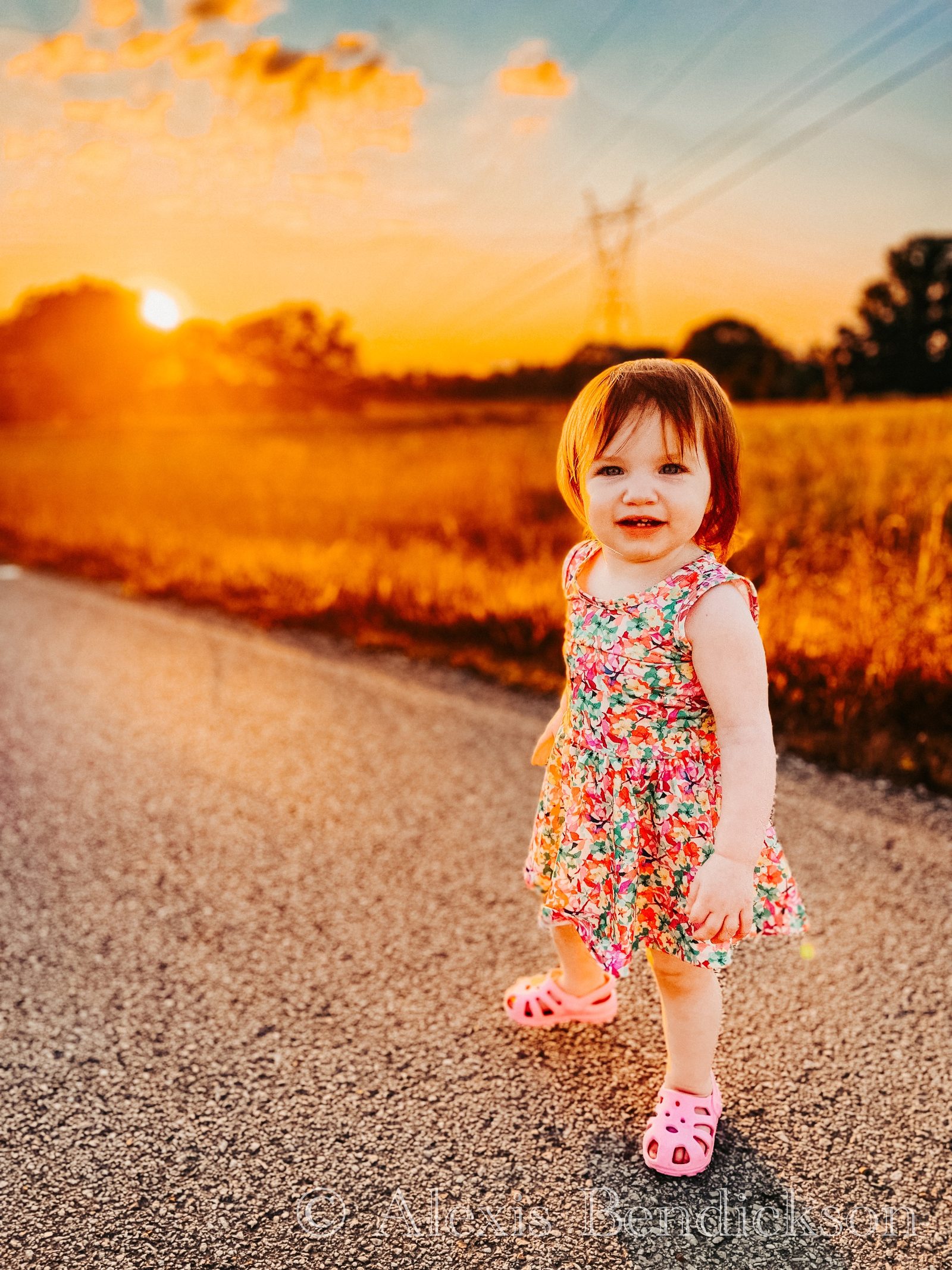 Emme standing on a country road at sunset, smiling