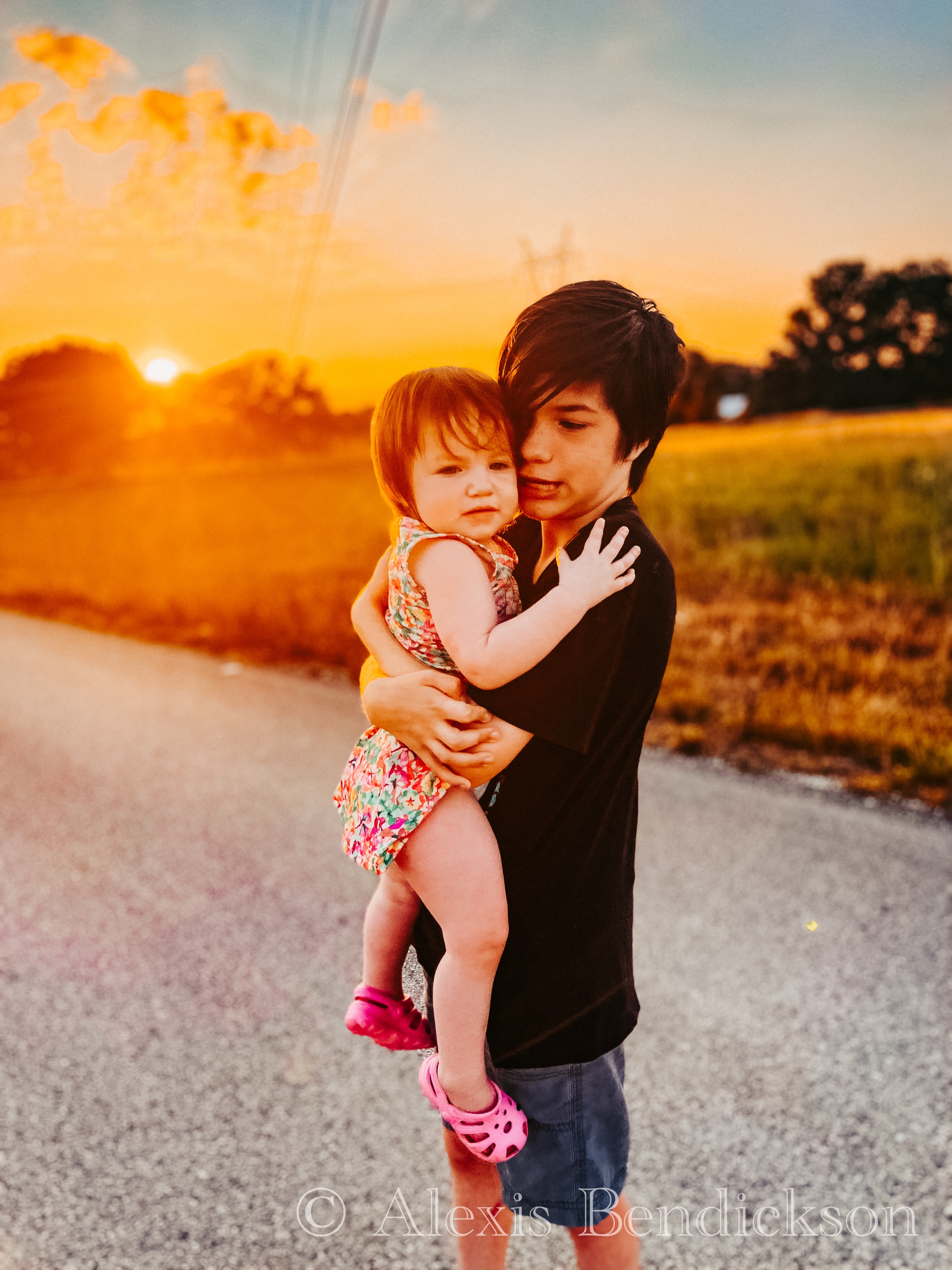 Noah holding Emme close, both glowing in golden sunset light