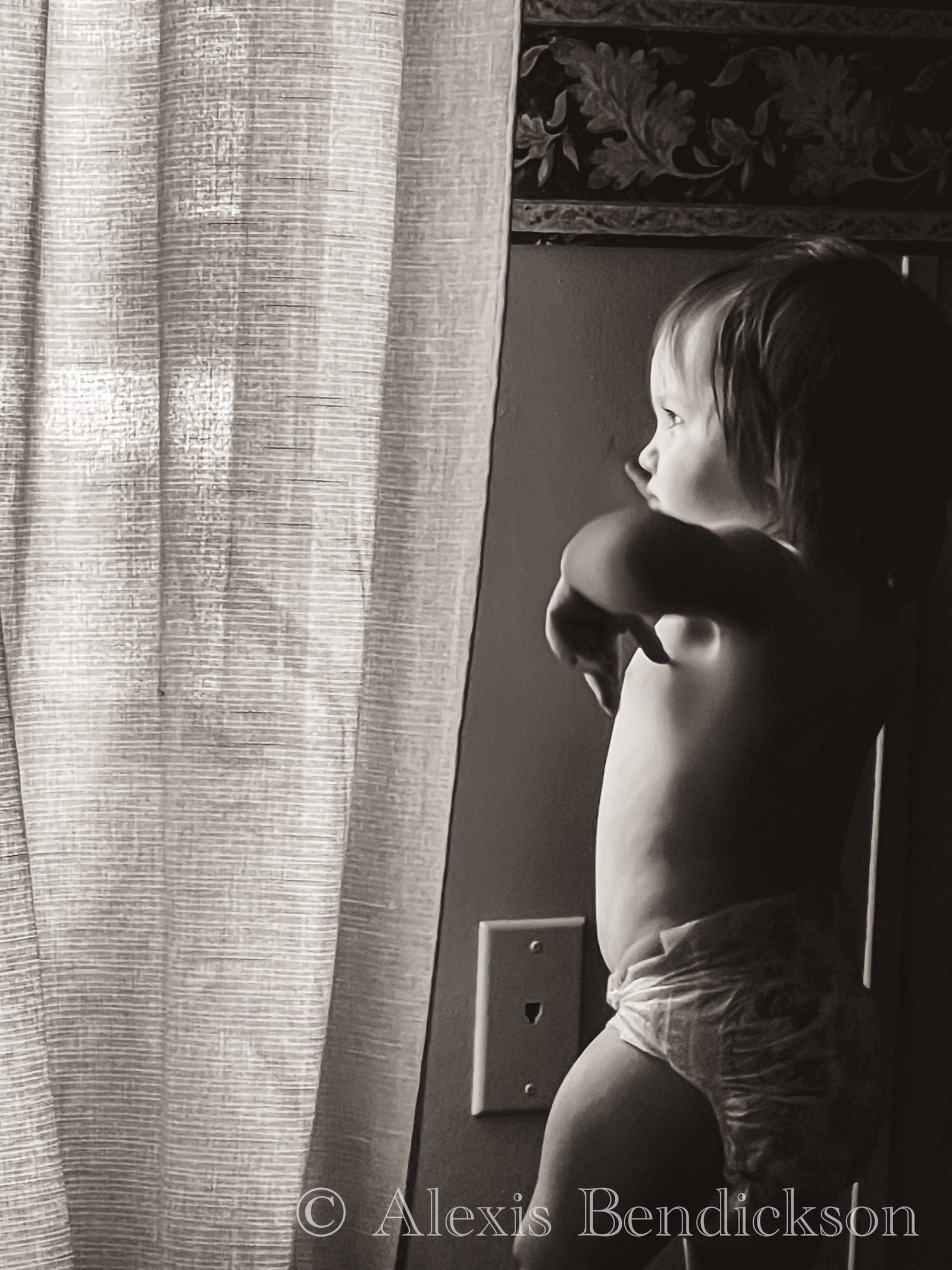 Toddler in a diaper gazing out the window, black and white
