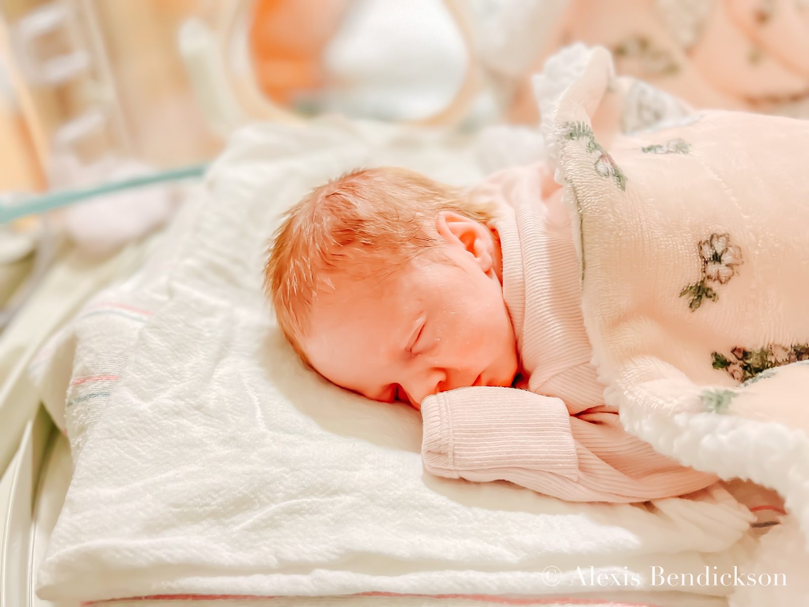 Emme sleeping in the NICU in a pink floral wrap, February 2022