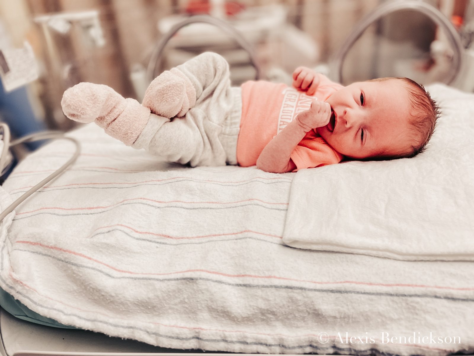 Emme awake in a 'NICU graduate' onesie, February 2022