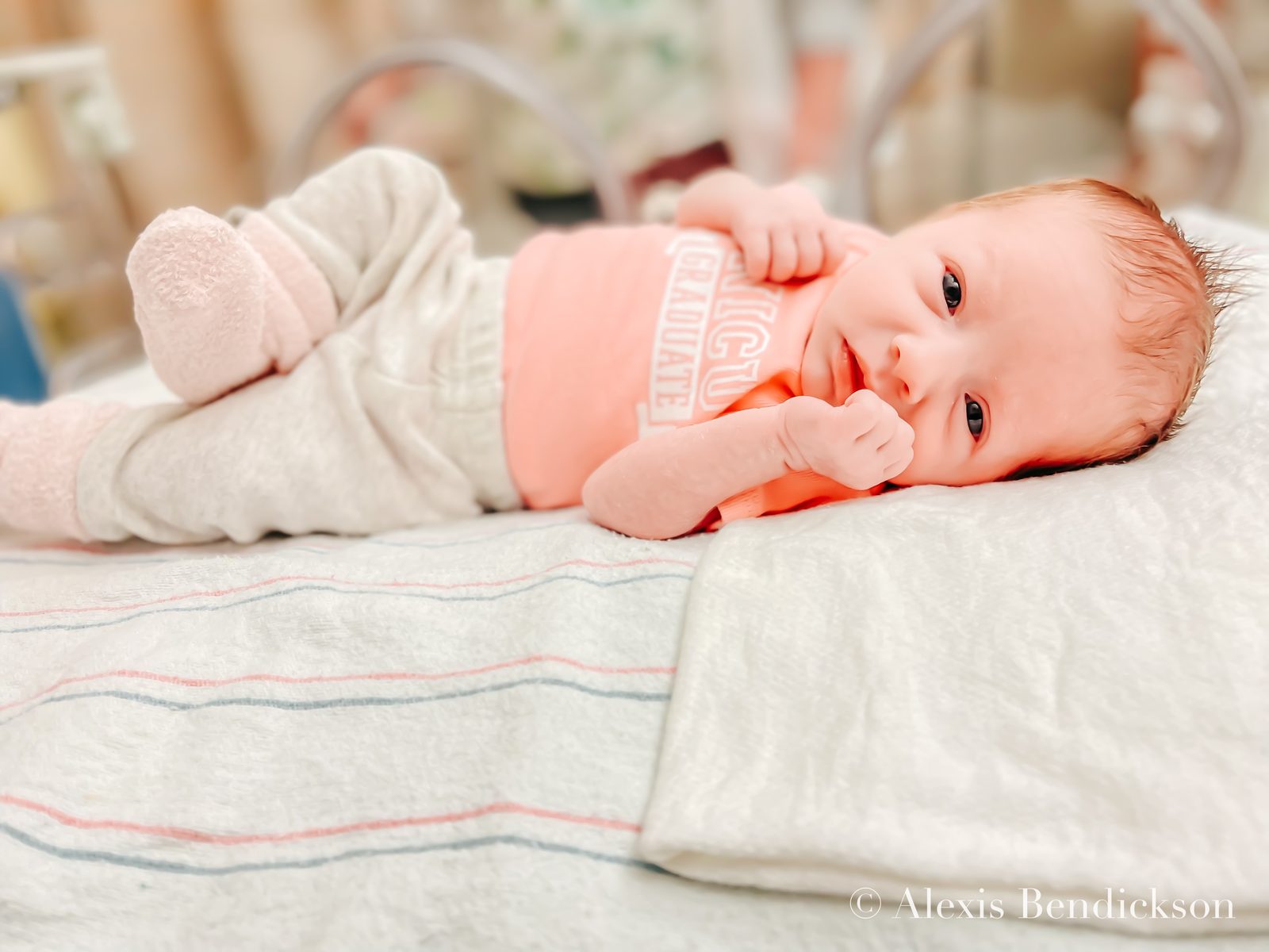 Emme smiling in a 'NICU graduate' onesie, February 2022