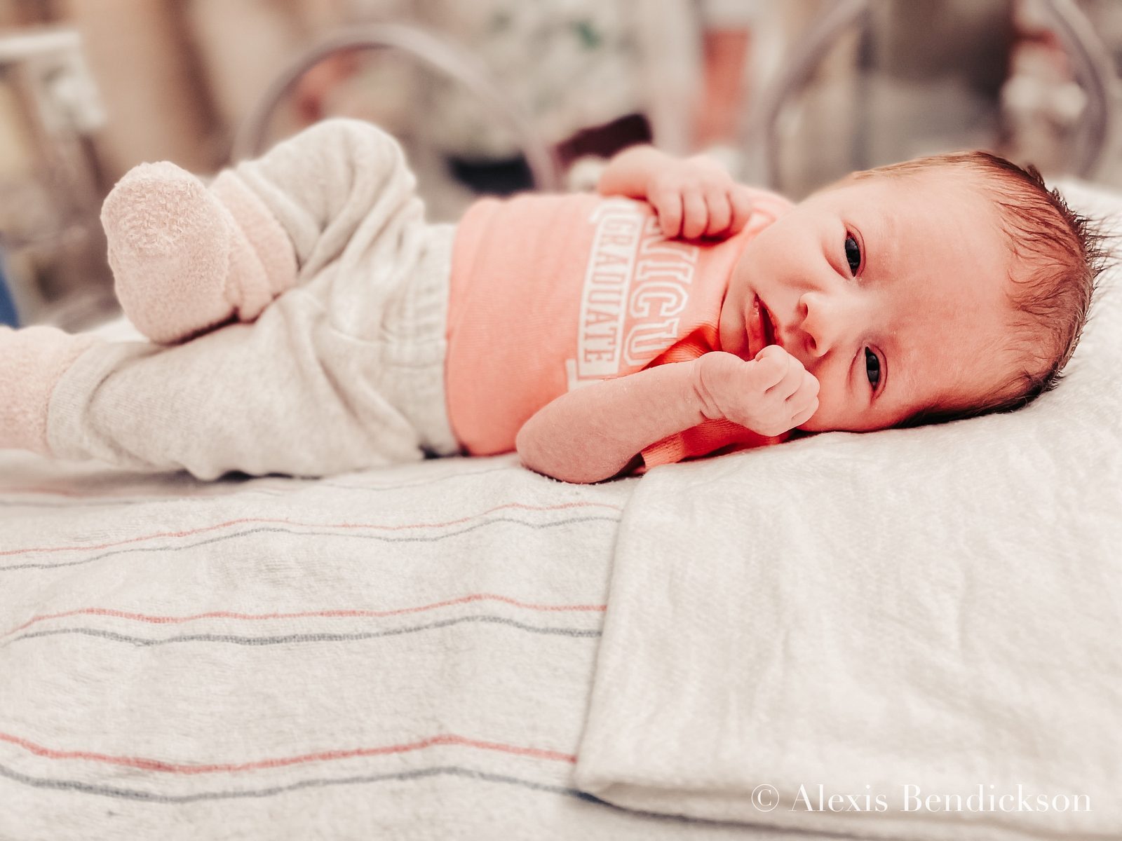 Emme in a 'NICU graduate' onesie with her feet up, February 2022
