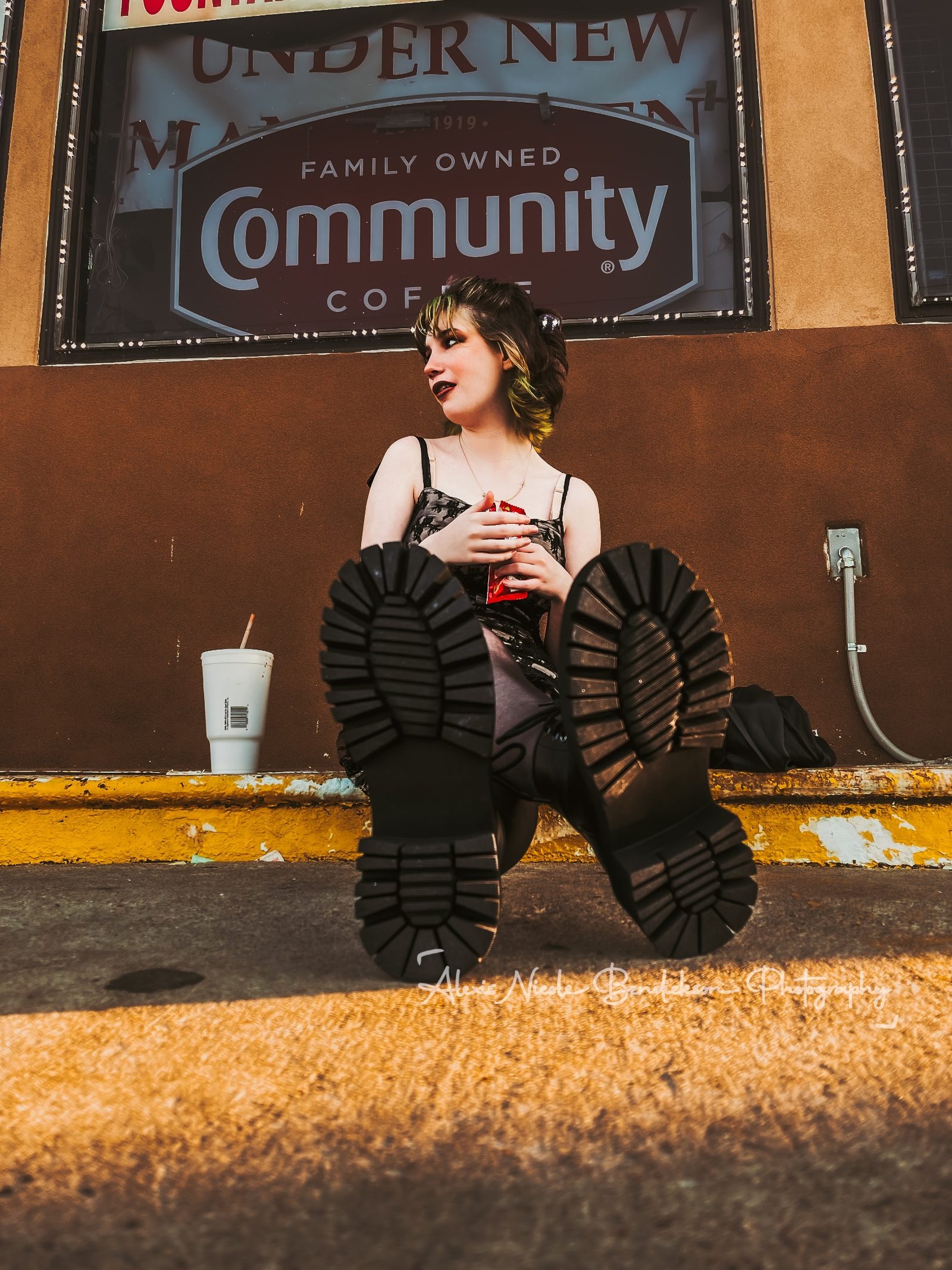 Low-angle shot of Lillia's boots with her holding a candy bar against a storefront